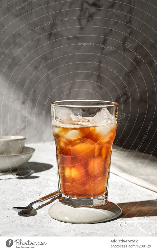 Ice tea in glass on table drink ice cold beverage refreshment serve tasty sweet spoon liquid delicious transparent portion flavor yummy taste fruit mix brown