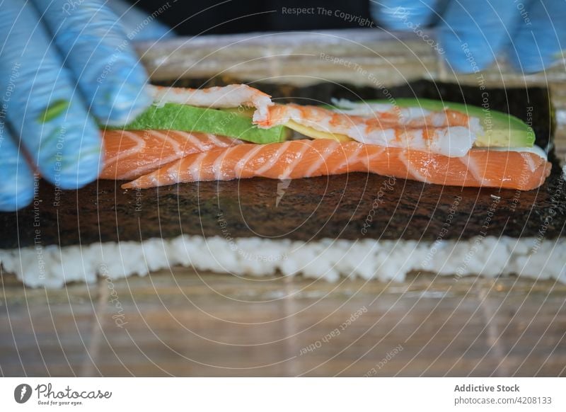 Detail of Chef Preparing Sushi chef cooking preparing sushi roll seaweed salmon fish unrecognized kitchen japanese restaurant professional occupation