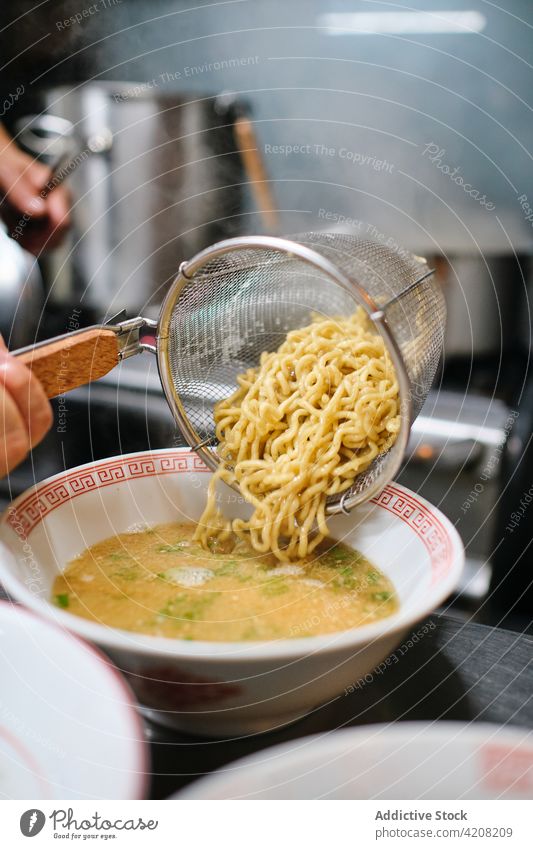 Detail of Noodles Soup Preparation ramen restaurant kitchen soup noodles yummy delicious japanese food plate strainer unrecognized front view faceless pouring