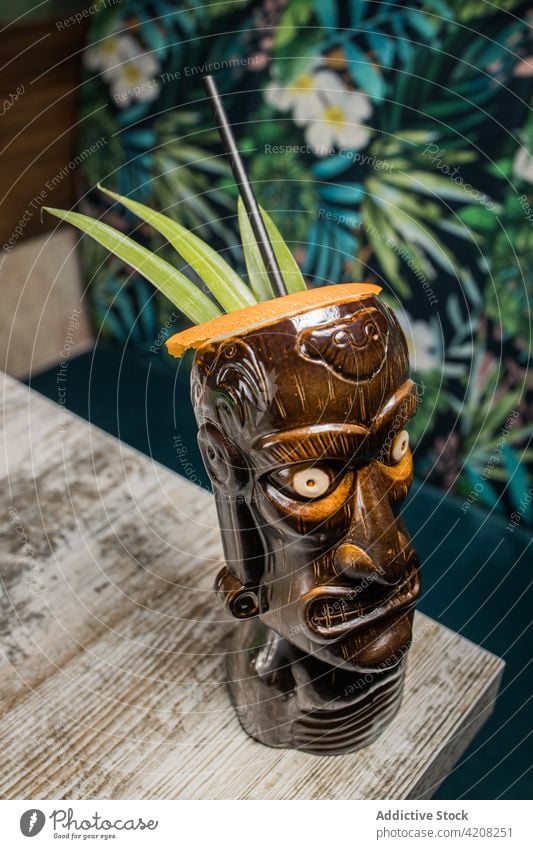 Polynesian tiki glass with cocktail mug beverage alcohol drink booze sculptural leaf colorful straw refreshment liquor glassware aperitif brown nautical cup