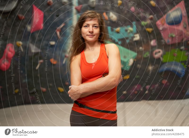 Sportswoman standing near climbing wall in gym sportswoman mountaineer climber smile confident fit fitness healthy athlete vitality energy charming strong