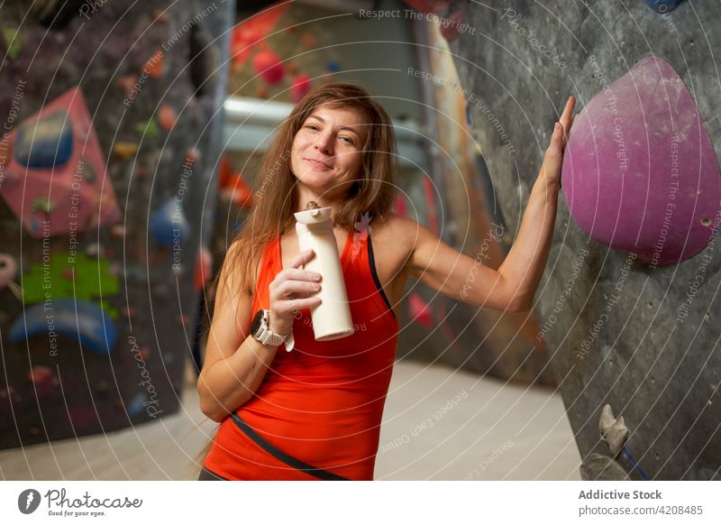 Happy woman with water in climbing center athlete climber gym lean on smile recreation break sport female healthy training bouldering mountaineer cheerful