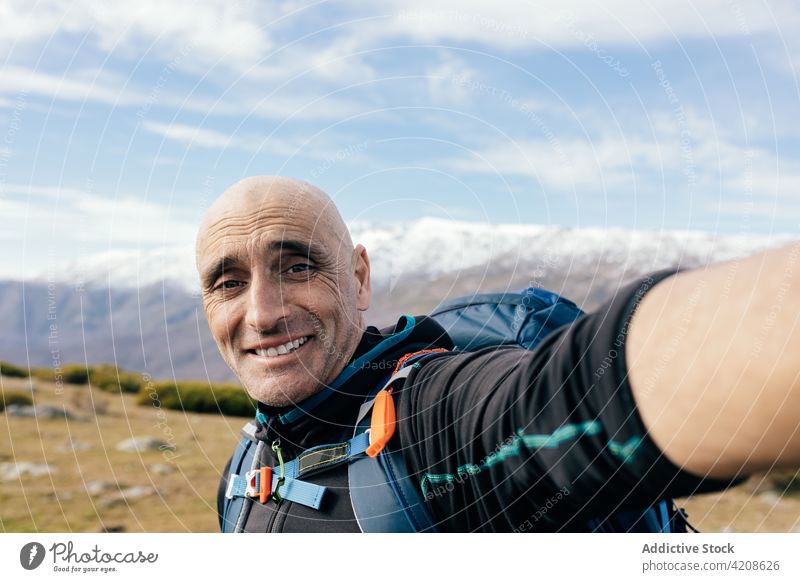 Happy traveler taking selfie in snowy mountains mountaineer climber man happy rock peak active nature freedom male adult landscape smile sunny self portrait