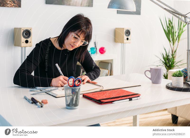 Creative woman drawing in sketchbook at home artist notepad creative talent female table room sit hobby imagination living room skill notebook inspiration