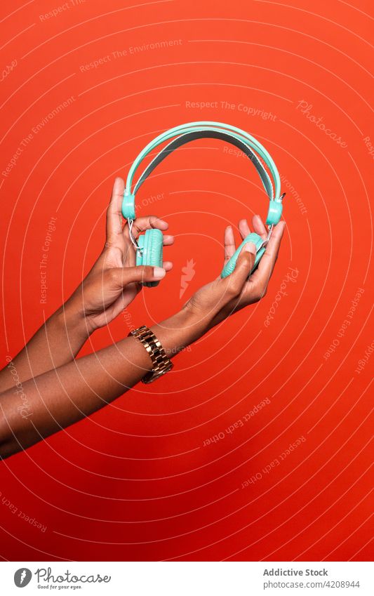 Crop unrecognizable black woman demonstrating modern headphones listen demonstrate music outstretch audio headset gadget wireless entertain song meloman sound