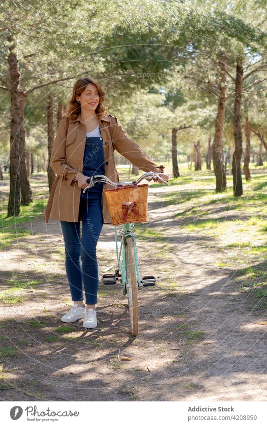Happy young woman near bicycle on dirt road happy smile cheerful park hobby positive female content activity old glad style timber wicker lady basket joy sunny