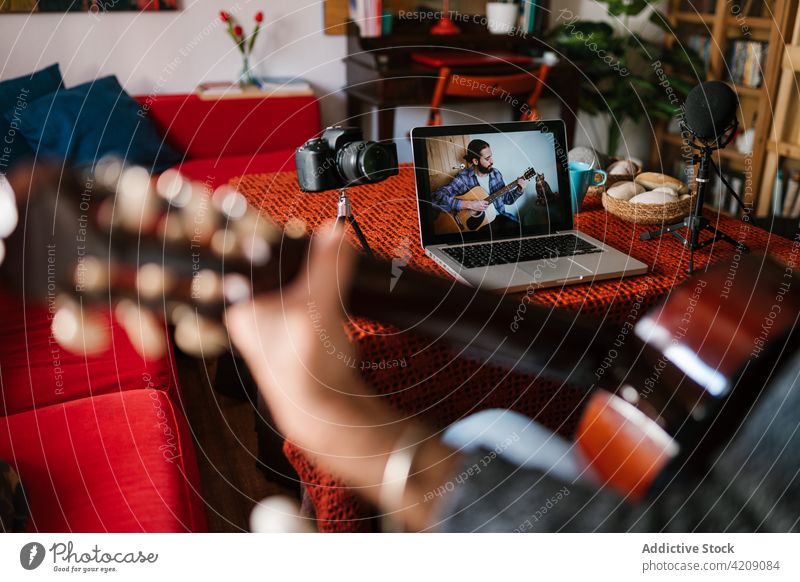 Crop Hispanic guitarist playing guitar while watching video on laptop lesson study learn man using gadget device screen knowledge musician acoustic art home