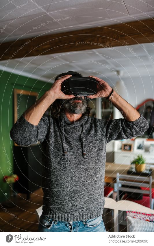 Anonymous bearded man experiencing virtual reality in goggles at home vr experience technology entertain spare time weekend using gadget device modern style