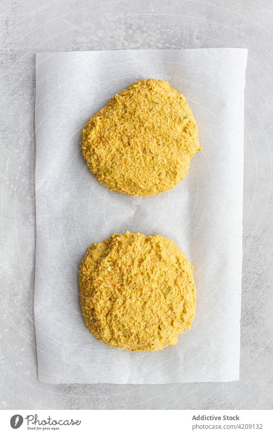Uncooked vegan chickpea cutlets on parchment burger food uncooked vegetarian homemade veggie meal prepare patty culinary raw curry crumb yellow spicy cuisine