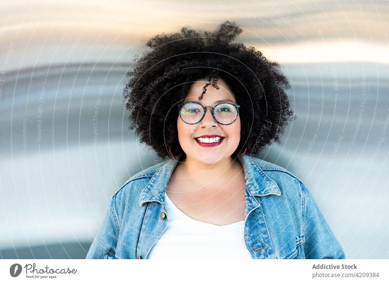 Stylish plump woman in eyeglasses and denim apparel style fashion dreamy afro hairstyle charming enjoy portrait smile friendly sincere overweight jacket