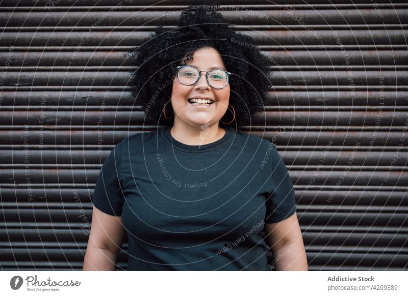 Happy plump woman in eyeglasses against ribbed wall laugh sincere friendly eyewear happy afro charming portrait overweight enjoy smile pleasant cheerful glad