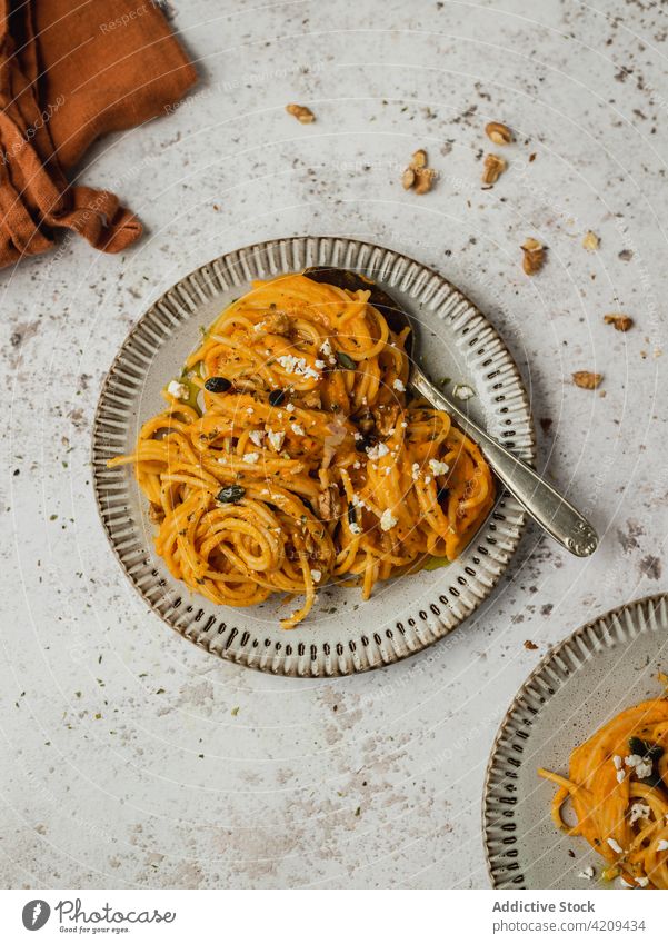 Appetizing pumpkin pasta in plate on table noodle dish lunch orange food serve tasty meal yummy ingredient cuisine nutrition seed garnish fresh palatable
