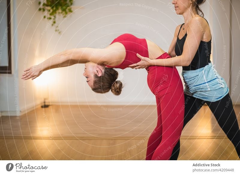 Flexible woman stretching body with instructor women bend back yoga help flexible asana together practice female stress relief coach zen class sportswear