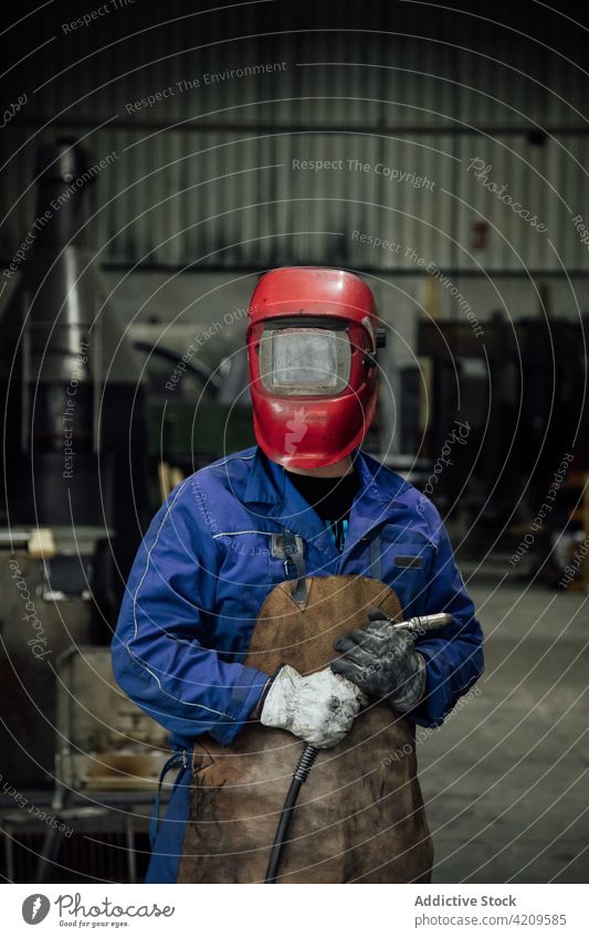 Unrecognizable welder in hardhat with welding hose in garage person mechanic workman workshop worker specialist equipment uniform construction employee tool