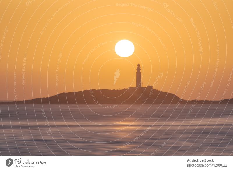 Bright sunset above ocean and coast with lighthouse shore sunrise ripple bright water environment faro de trafalgar cadiz spain high rise picturesque scenery