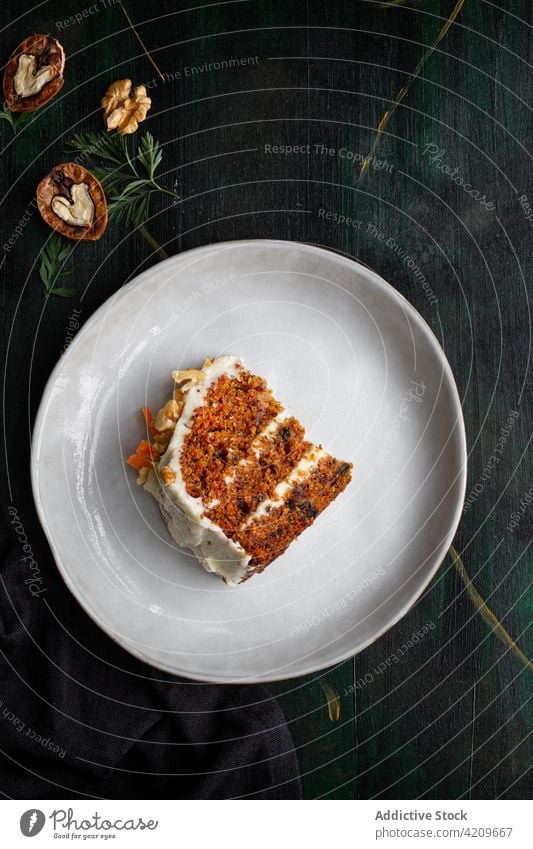 Tasty carrot cake piece on plate with walnuts dessert treat sweet yummy portion cutlery delicious cream cheese homemade knife soft spoon crunchy vitamin smooth