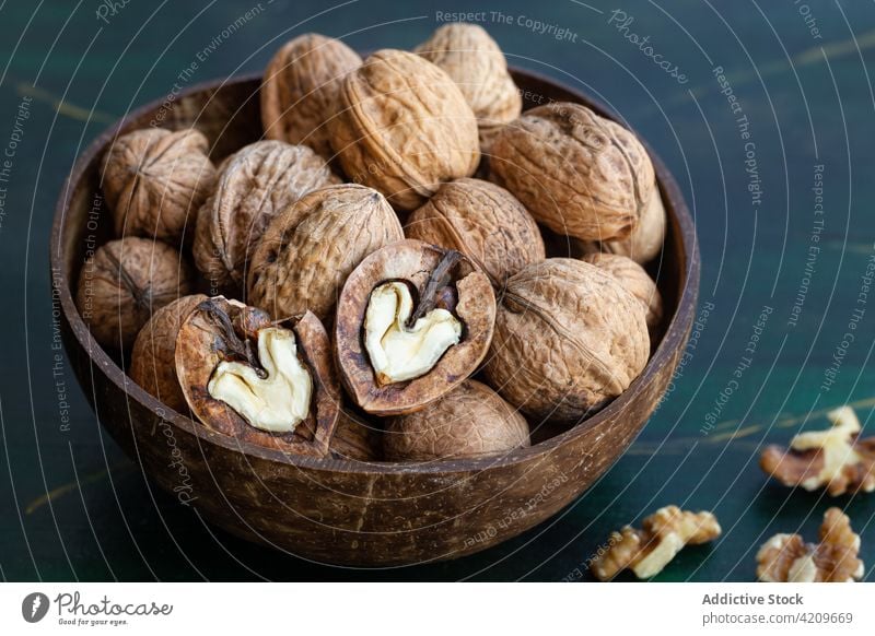 Bowl with walnuts on table nutrient vitamin snack protein crunchy natural bowl ingredient vegan wooden round shape dry uneven nutshell material full pile edible
