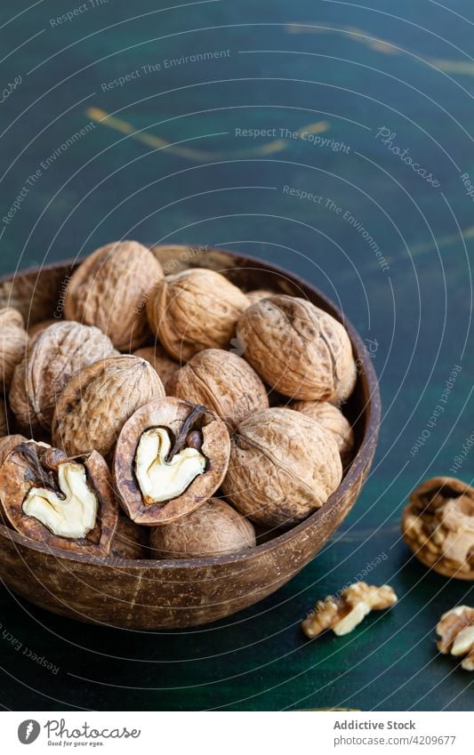 Bowl with walnuts on table nutrient vitamin snack protein crunchy natural bowl ingredient vegan wooden round shape dry uneven nutshell material full pile edible