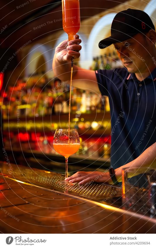 Young Asian bartender pouring grapefruit juice in the glass while preparing a cocktail in the bar alcohol alcoholic aperitif barista barman beverage bottle