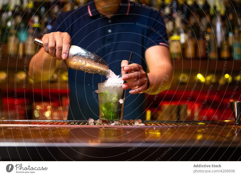 Unrecognizable bartender pouring crushed ice to the glass while preparing a cocktail in the bar alcohol alcoholic aperitif barista barman beverage club