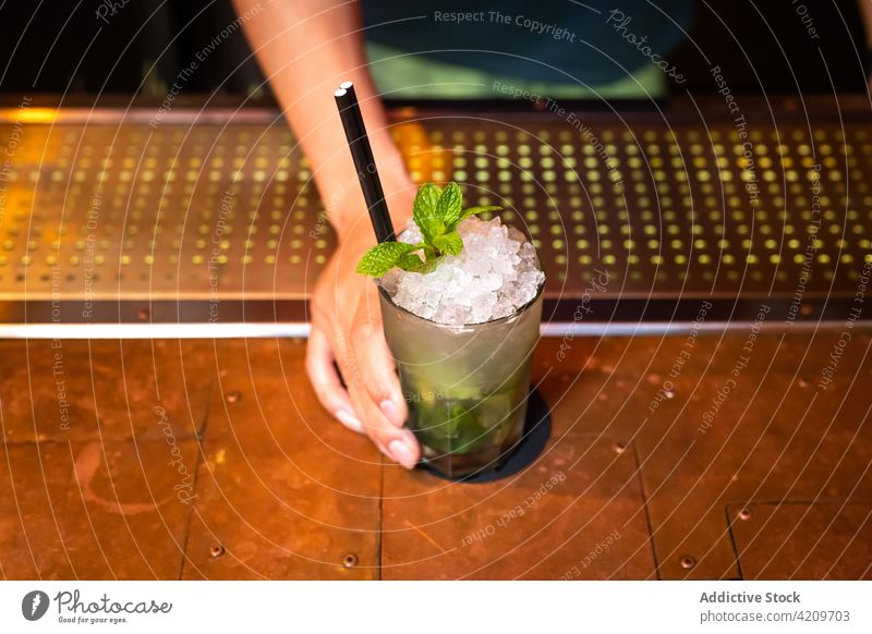 Hand of unrecognizable bartender gives you well elaborated mojito cocktail in the bar alcohol alcoholic aperitif barista barman beverage bottle business club