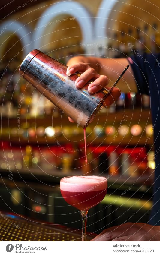 Detail of bartender's hand working in the bar with his shaker and pouring a cocktail in the glass alcohol alcoholic aperitif barista barman beverage bottle
