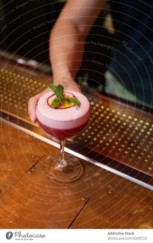 Unrecognizable bartender serving a cocktail with mint leaves and passion fruit in the bar alcohol alcoholic aperitif barista barman beverage business club