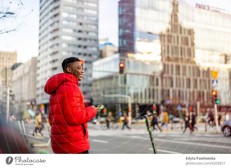 Portrait of a young man standing in a city street, smiling black outside urban millennial African outdoors Warsaw one real people casual lifestyle guy