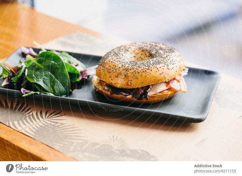 Tasty bagel sandwich on table in cafe meat serve tasty chicken appetizing food meal delicious salad plate rucola arugula cheese culinary nutrition portion