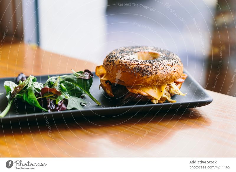 Tasty bagel sandwich on table in cafe meat serve tasty chicken appetizing food meal delicious salad plate rucola arugula cheese culinary nutrition portion