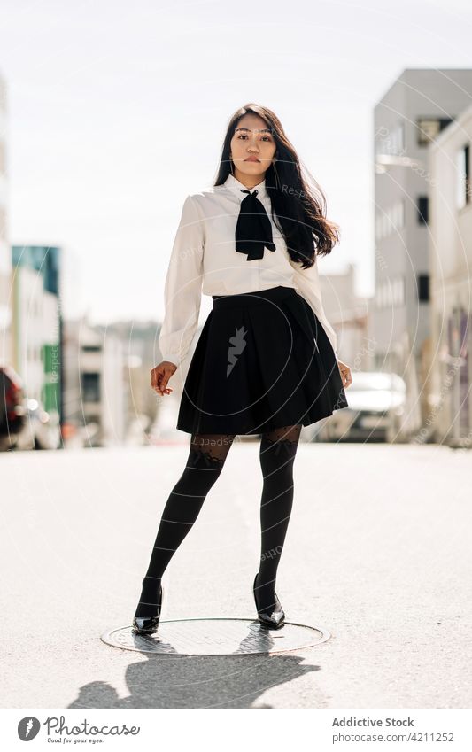 Confident ethnic woman in elegant outfit standing on road personality charismatic posture stare cool confident individuality appearance female urban millennial
