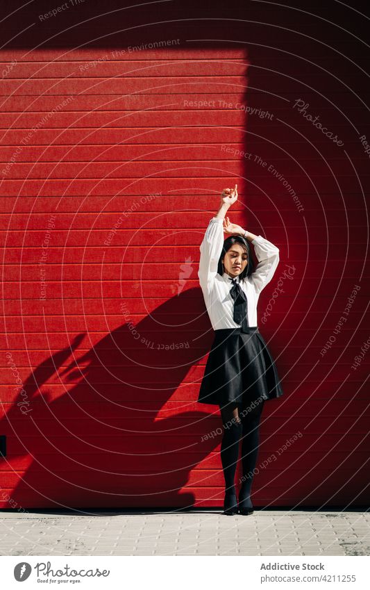 Woman in skirt and blouse standing near red door woman individuality urban style sunlight millennial youth personality gate female shadow sunshine cool wall