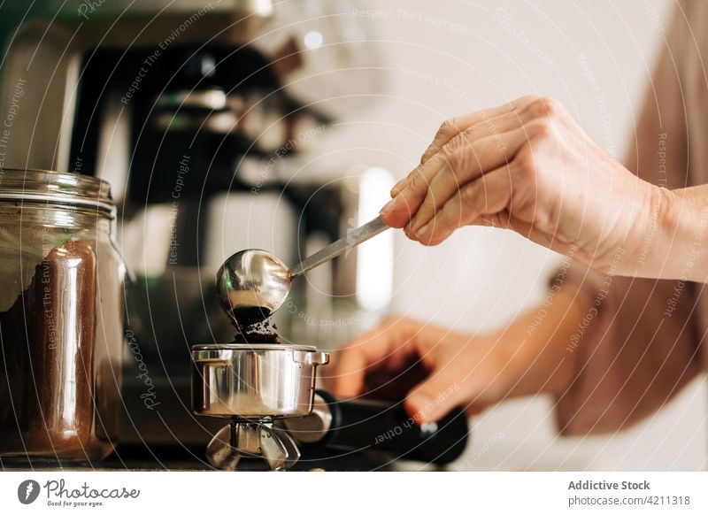 Crop woman pouring coffee into portafilter hand prepare coffeemaker coffee machine kitchen equipment kitchenware domestic female home professional apartment