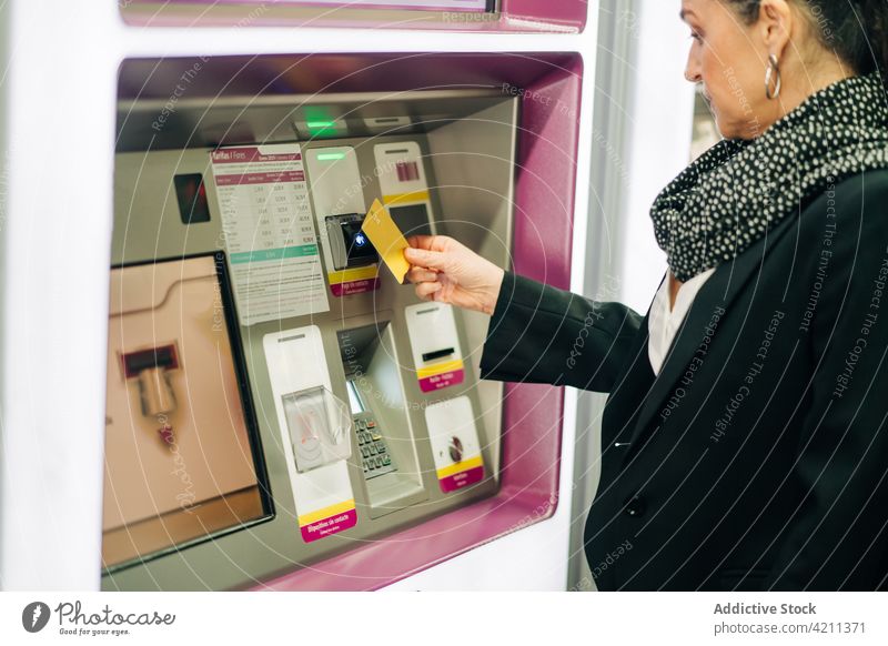 Crop woman buying ticket in terminal atm journey pay card railway station payment passenger electronic modern female serious transaction automatic machine