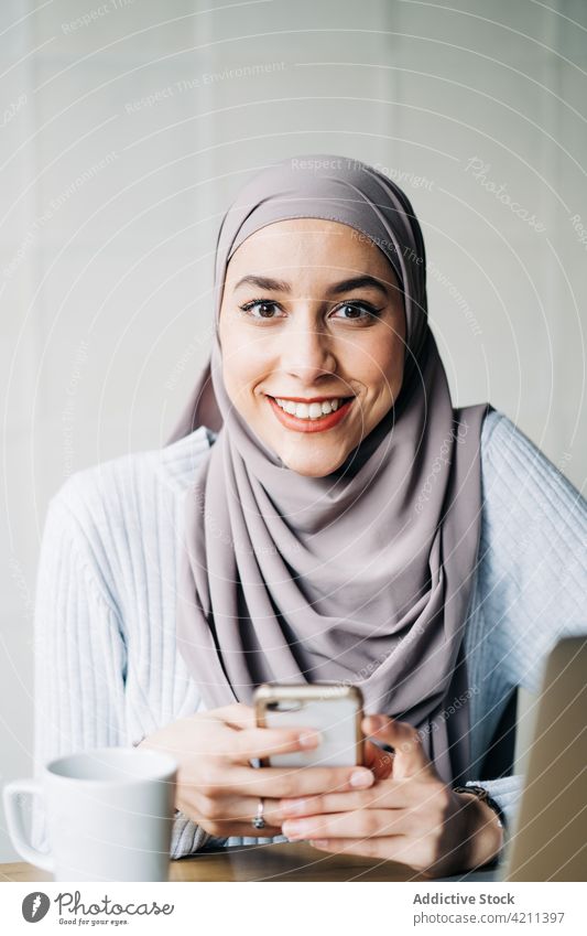 Portrait of Muslim female entrepreneur using smartphone woman muslim work freelance cafe ethnic table remote portrait gadget device cellphone mobile occupation