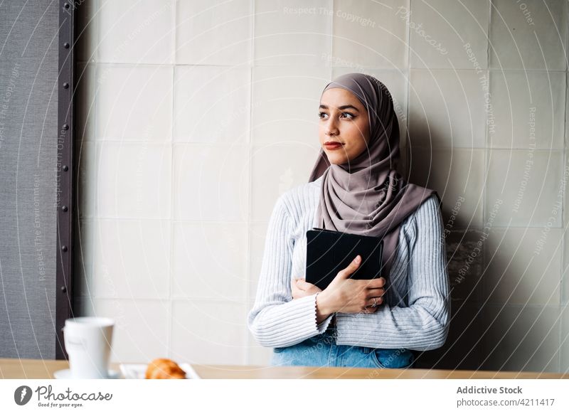 Ethnic woman in headscarf using tablet in cafe browsing freelance work project surfing hijab female ethnic muslim gadget connection remote distance business
