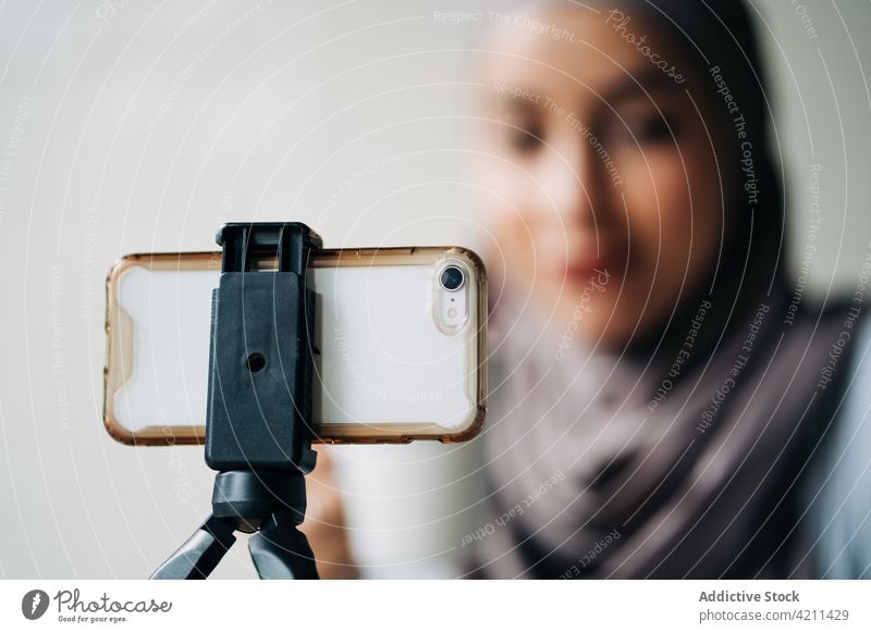 Ethnic woman recording video for blog in cafe blogger smartphone influencer social media using female ethnic muslim hijab headscarf table gadget device tripod