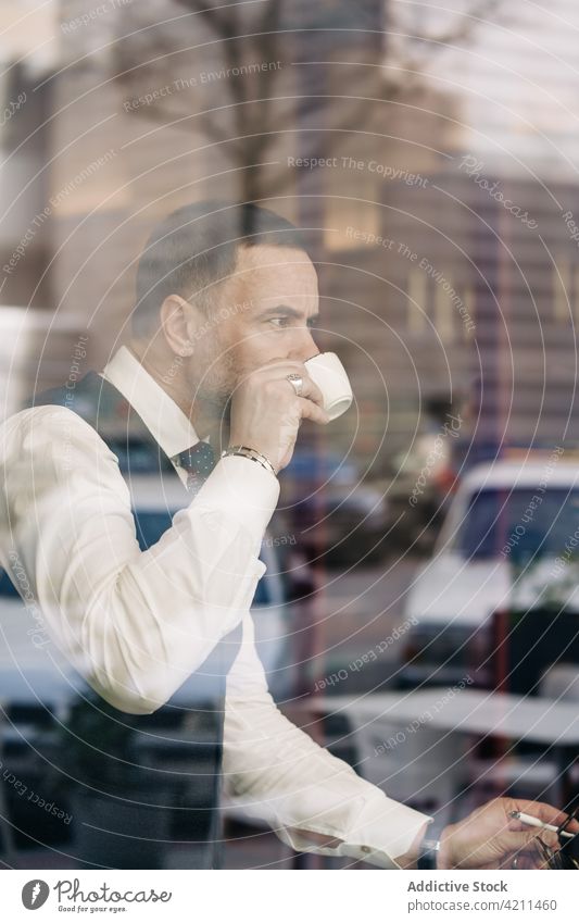 Stylish ethnic businessman drinking coffee in cafeteria formal style masculine hot drink reflection glass wall entrepreneur self employed enjoy serious beverage