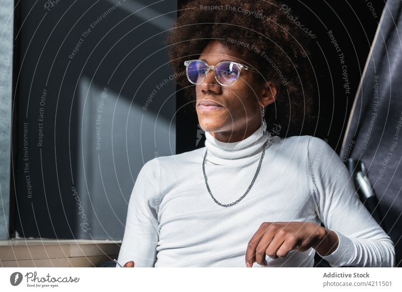 Stylish young African American guy chilling in cafe in sunlight man pensive fashion style alone recreation appearance personality tranquil individuality male