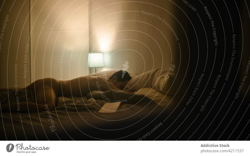 Naked man sleeping on bed at home naked dim light cozy nude bedroom lying male soft calm tranquil relax domestic apartment evening night serene quiet harmony