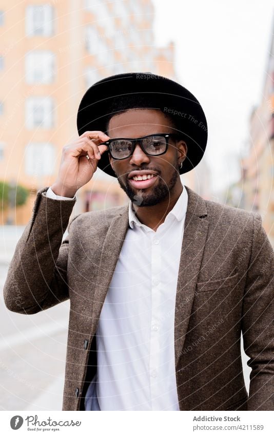 Trendy black man standing on street and looking at camera style hat jacket handsome glasses trendy masculine city male ethnic african american urban outfit