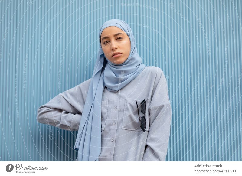 Dreamy ethnic woman in headscarf on blue background melancholy wistful lonely sincere contemplate pensive islam portrait style casual modern color thoughtful