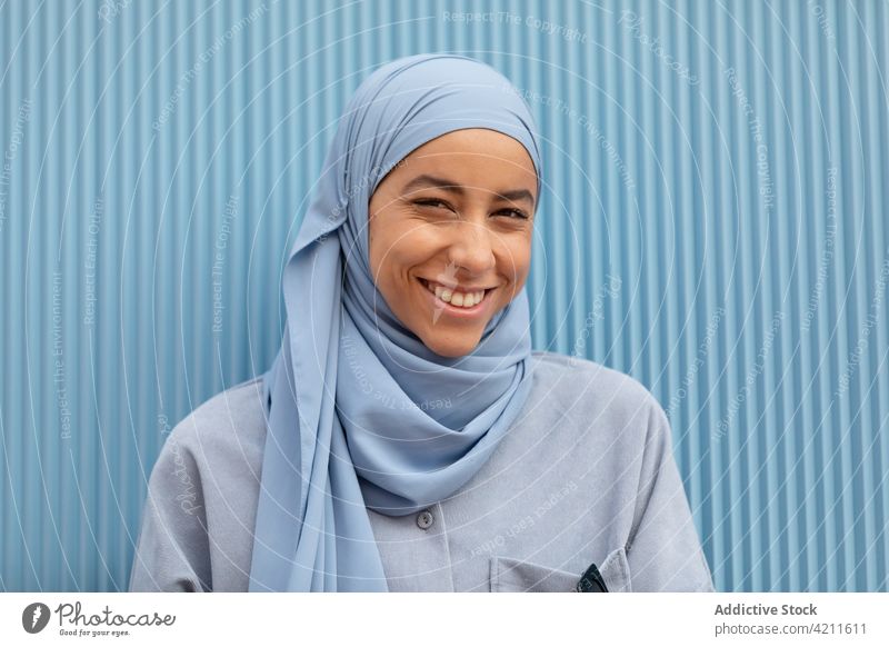 Happy ethnic woman in headscarf on blue background melancholy wistful lonely sincere contemplate islam portrait style casual modern color thoughtful dreamy