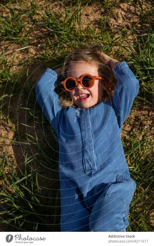 Stylish girl lying on grass rest style outfit field lawn weekend hand behind head summer kid child season sunglasses trendy peaceful chill carefree garment