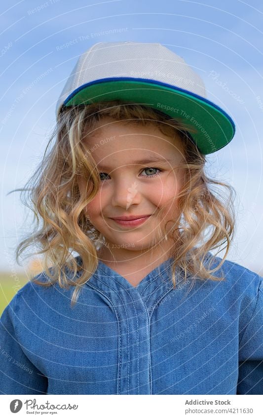 Trendy girl in grassy meadow field summer nature style outfit rest weekend sunny daytime child casual fashion trendy cap freedom season cute childhood kid