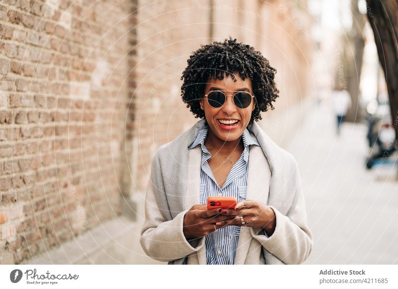 Smiling black woman with smartphone using smile happy connection fun joy digital female carefree delight internet browsing mobile glad content gadget positive