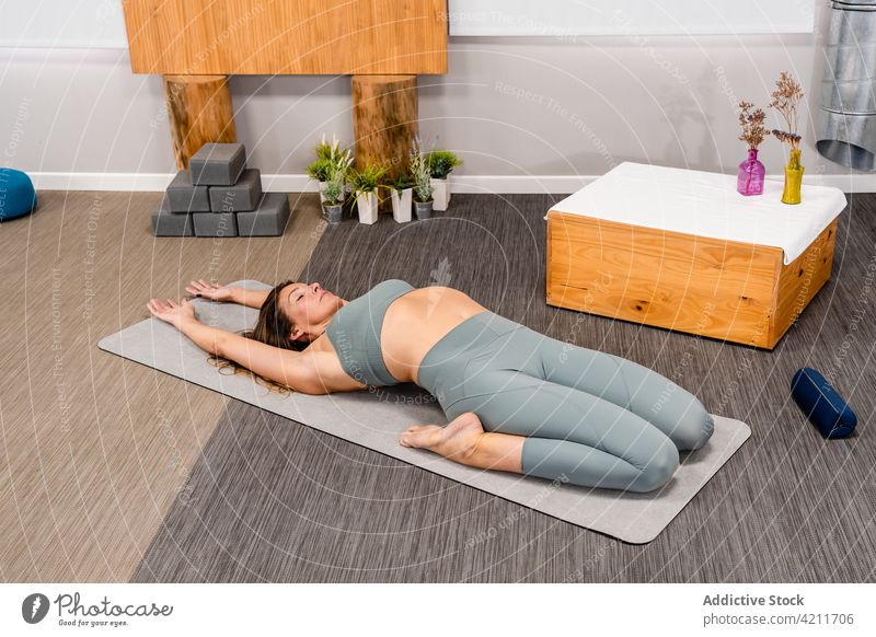 Relaxed young woman lying on mat Extended Supine Hero yoga asana extended supine hero utthita supta virasana eyes closed recreation stress relief mindfulness