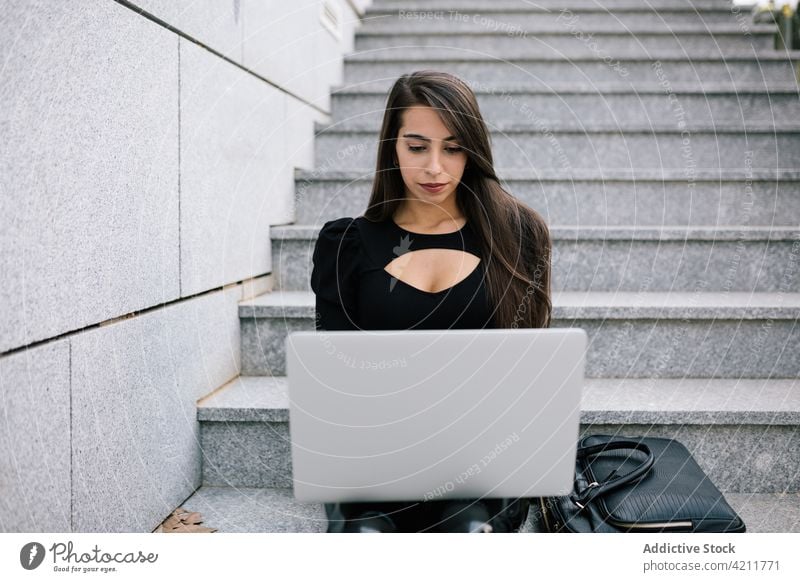 Businesswoman typing on laptop in city businesswoman work remote browsing distance project online female entrepreneur stone sit stair step surfing using