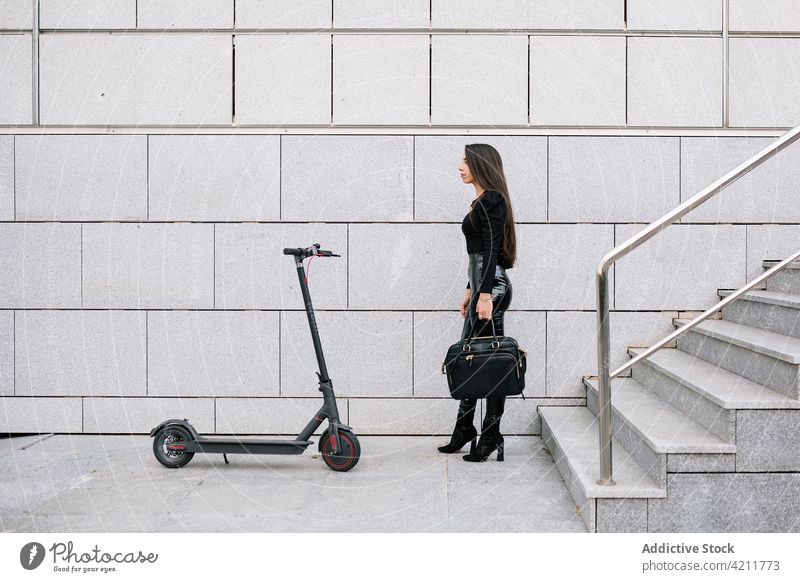 Stylish businesswoman standing near electric scooter in city transport street entrepreneur style modern urban female step confident trendy stair manager commute