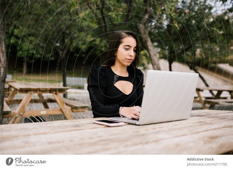 Businesswoman working in urban park businesswoman laptop remote female entrepreneur table browsing focus device netbook freelance sit occupation typing using